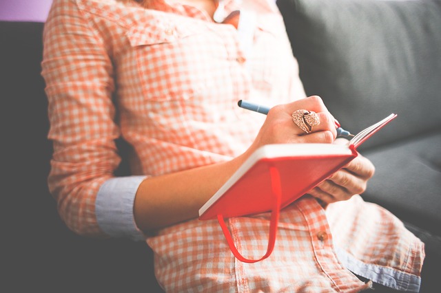 Mujer escribiendo frases motivacionales para emprendedores en bloc de notas